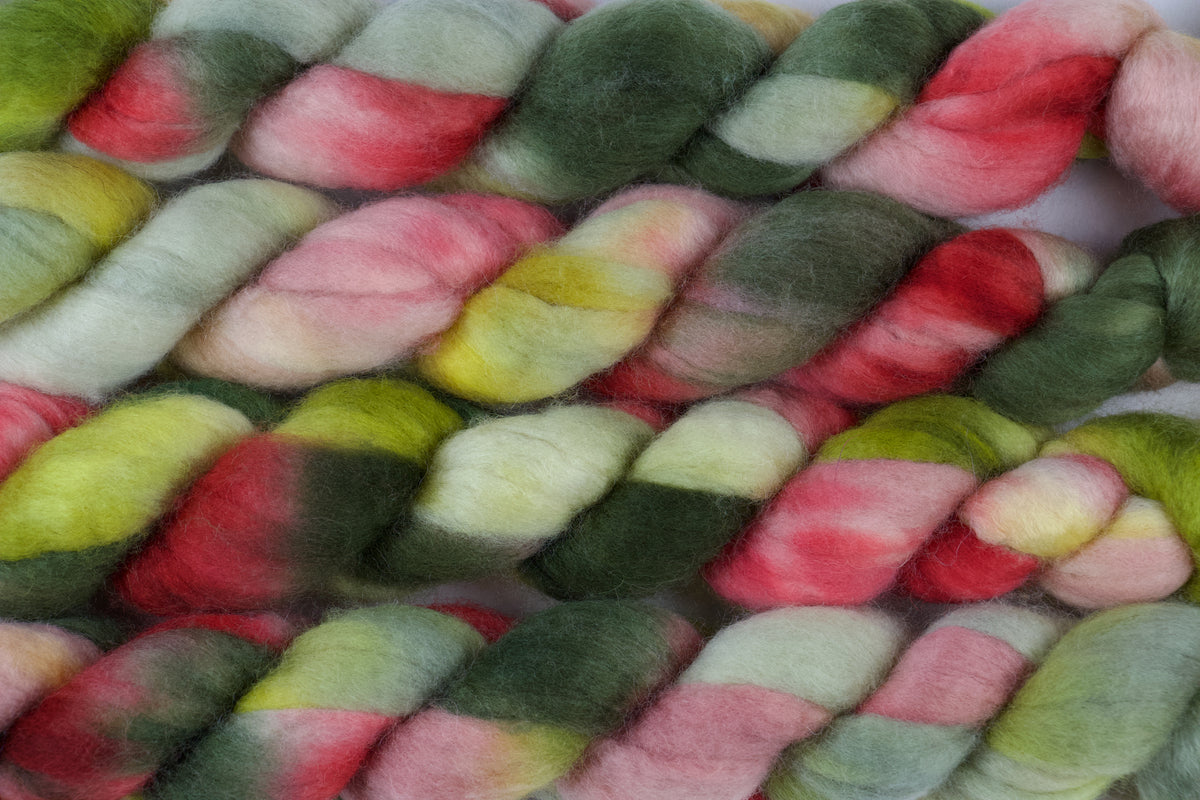 Braided fiber skein with pink, red, and green on a white background