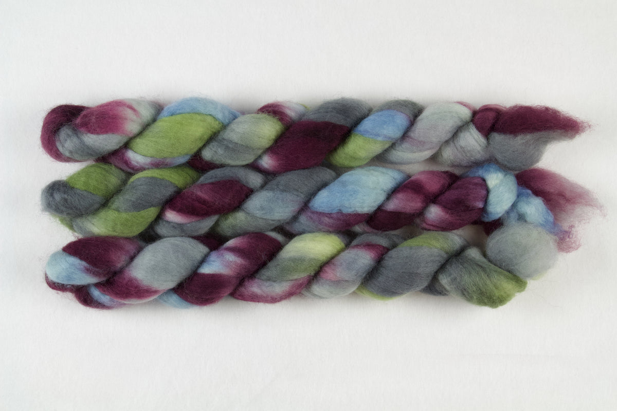 Braided fiber skein with blue, red, gray, and green on a white background
