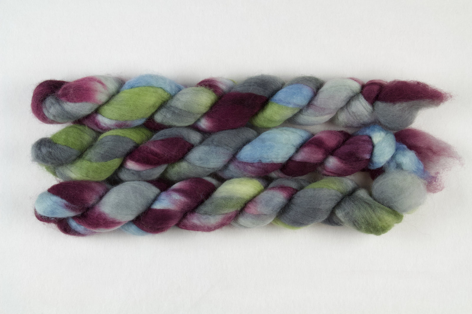 Braided fiber skein with blue, red, gray, and green on a white background