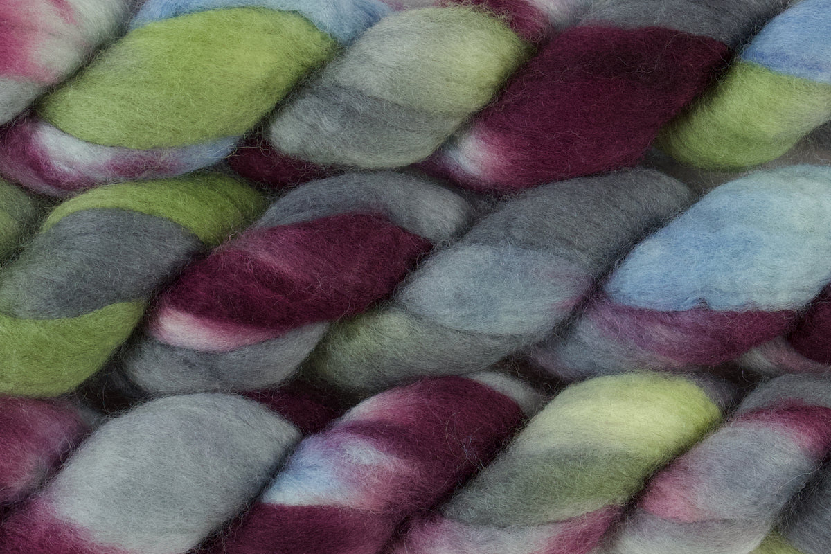 Braided fiber skein with blue, red, gray, and green on a white background