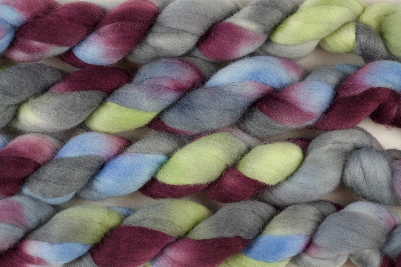 Braided fiber skein with blue, red, gray, and green on a white background