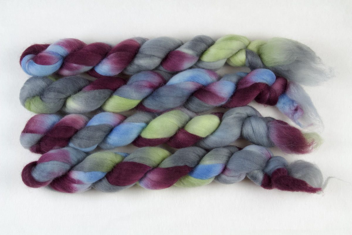 Braided fiber skein with blue, red, gray, and green on a white background