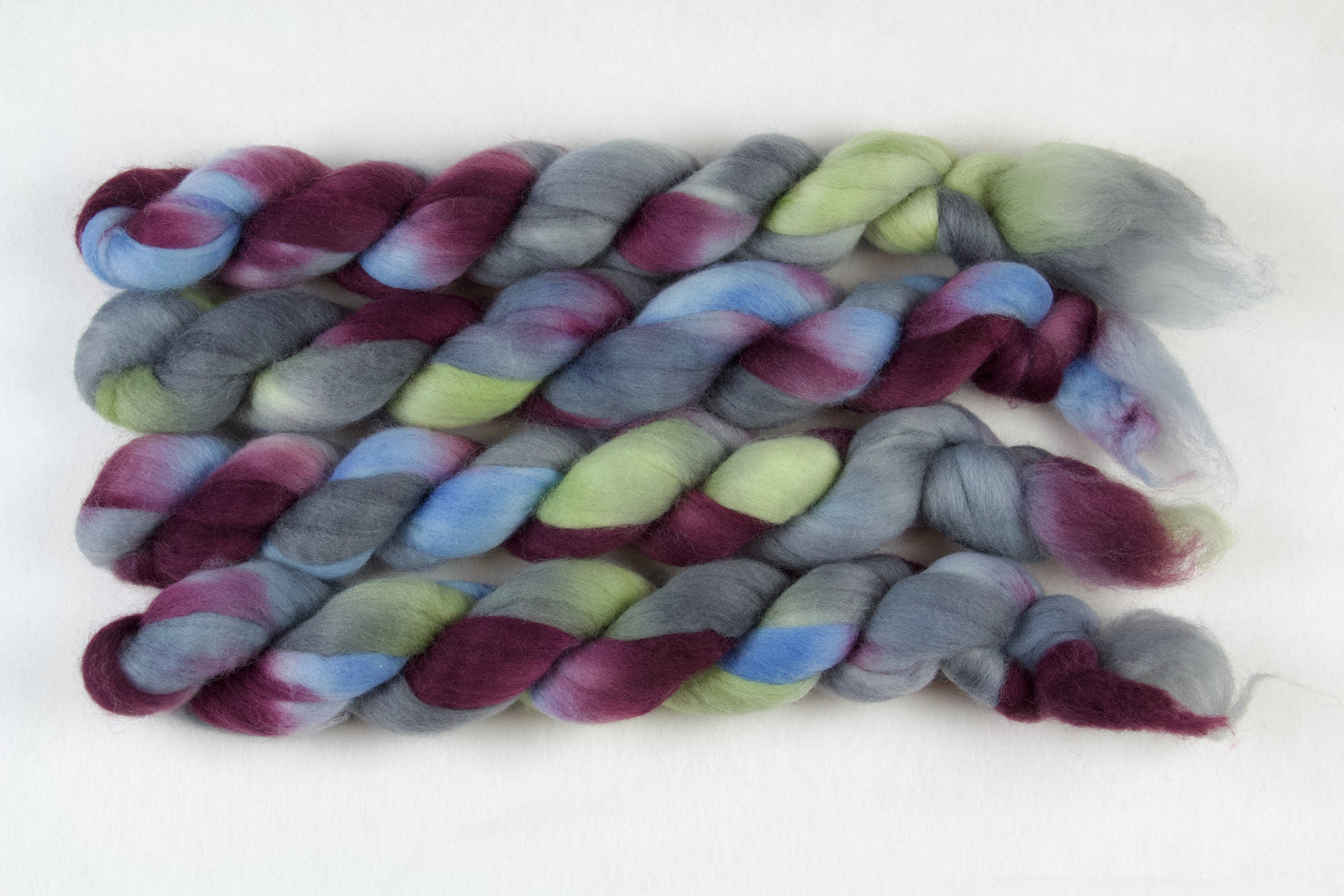 Braided fiber skein with blue, red, gray, and green on a white background