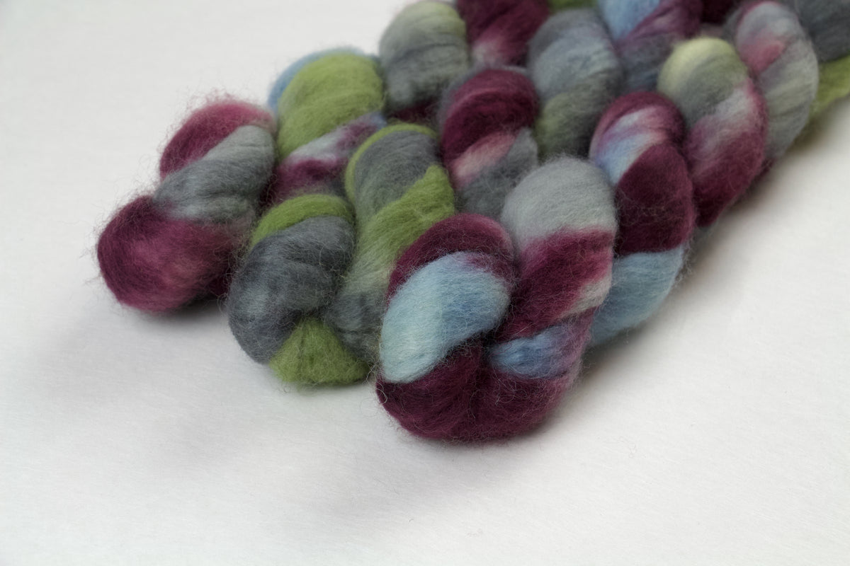 Braided fiber skein with blue, red, gray, and green on a white background