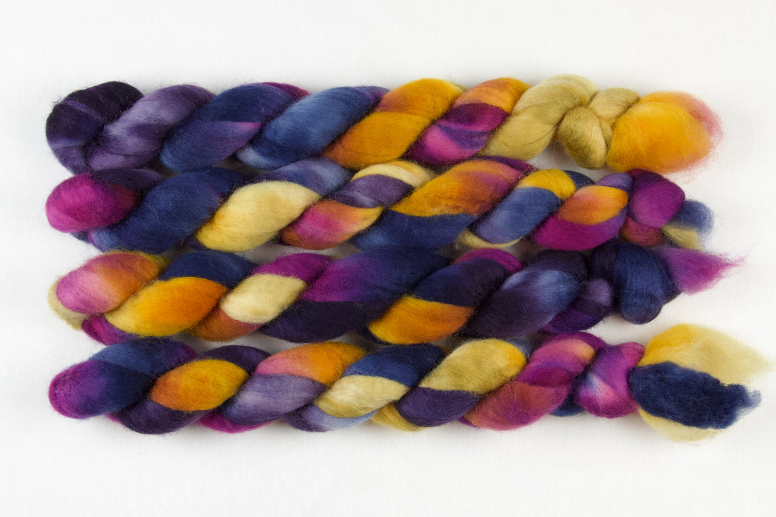 Braided fiber skein with blue, purple, pink, and gold on a white background