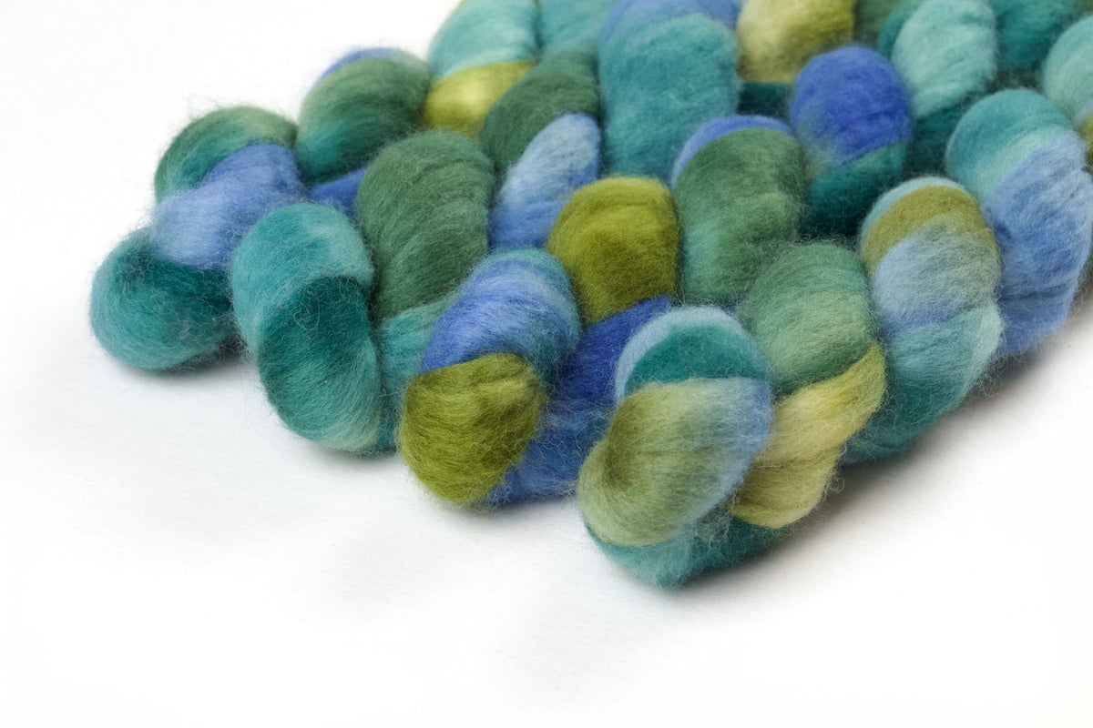 Braided fiber skein with blue, teal,  and green on a white background