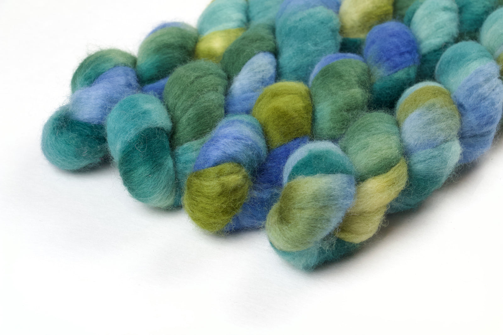 Braided fiber skein with blue, teal,  and green on a white background