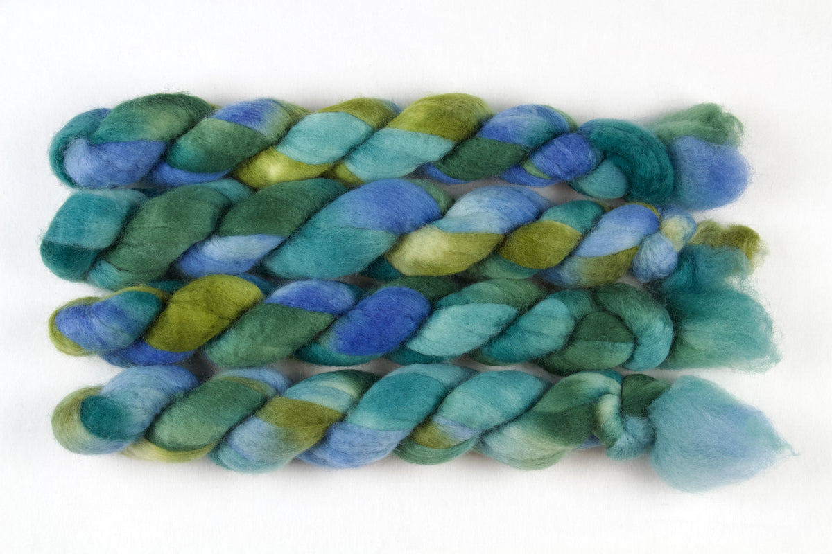 Braided fiber skein with blue, purple, and pink on a white background