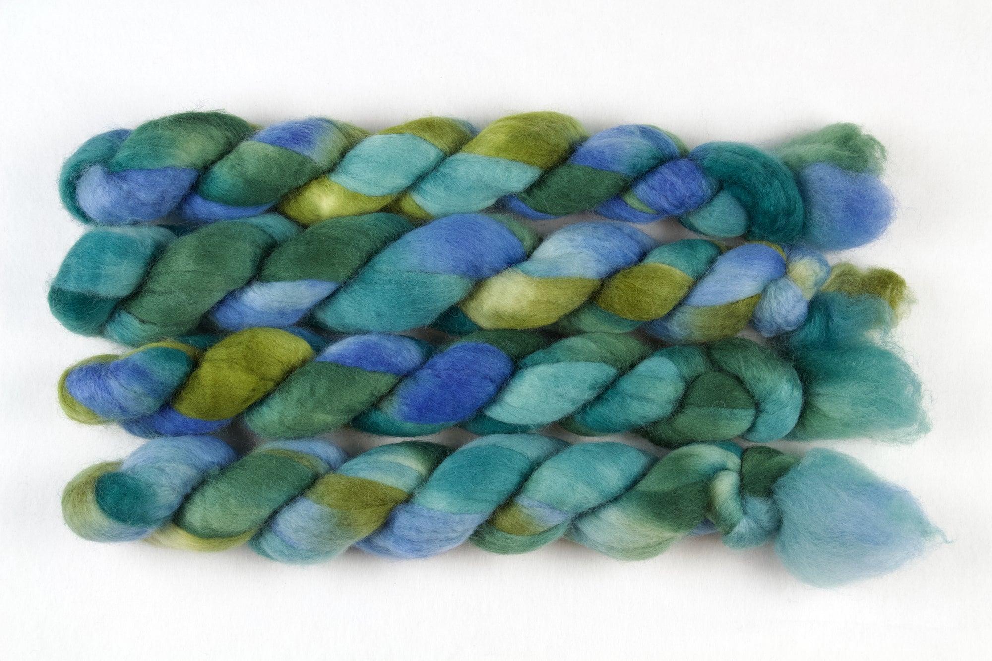 Braided fiber skein with blue, teal,  and green on a white background