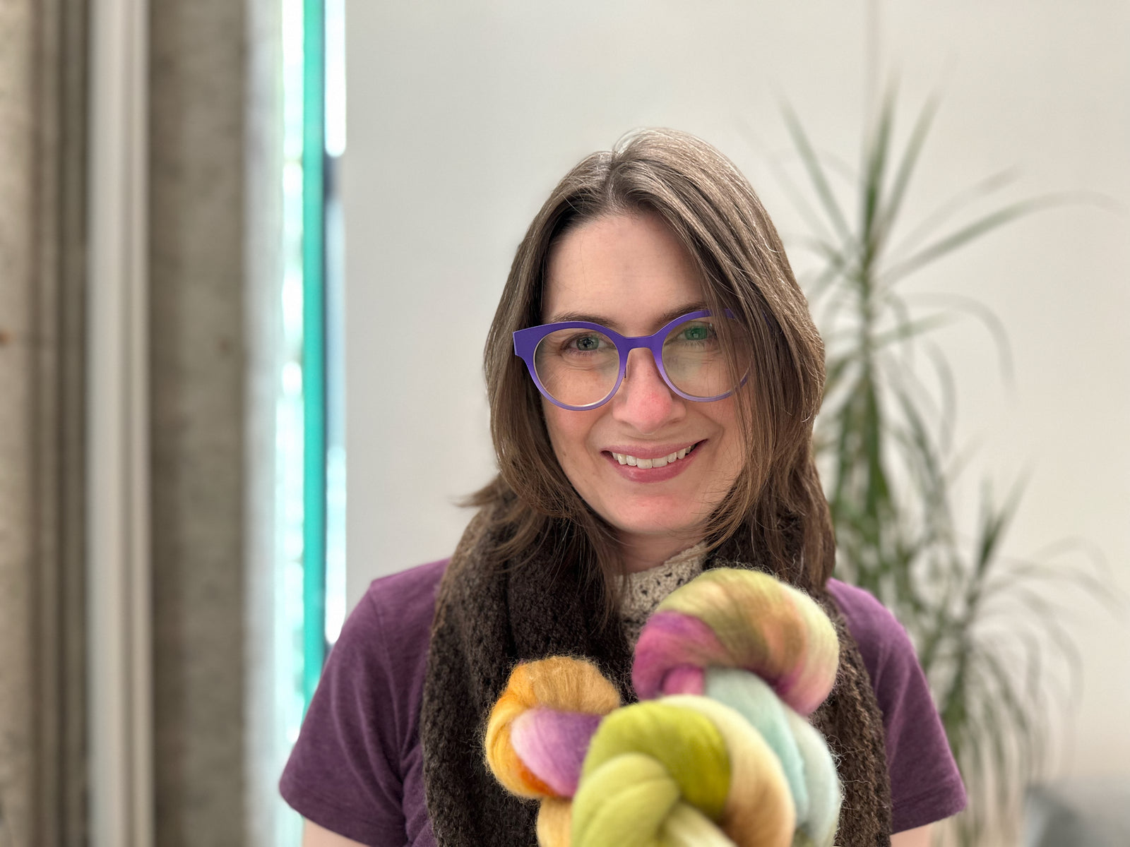 Miryha  holding colorful fiber in an indoor setting