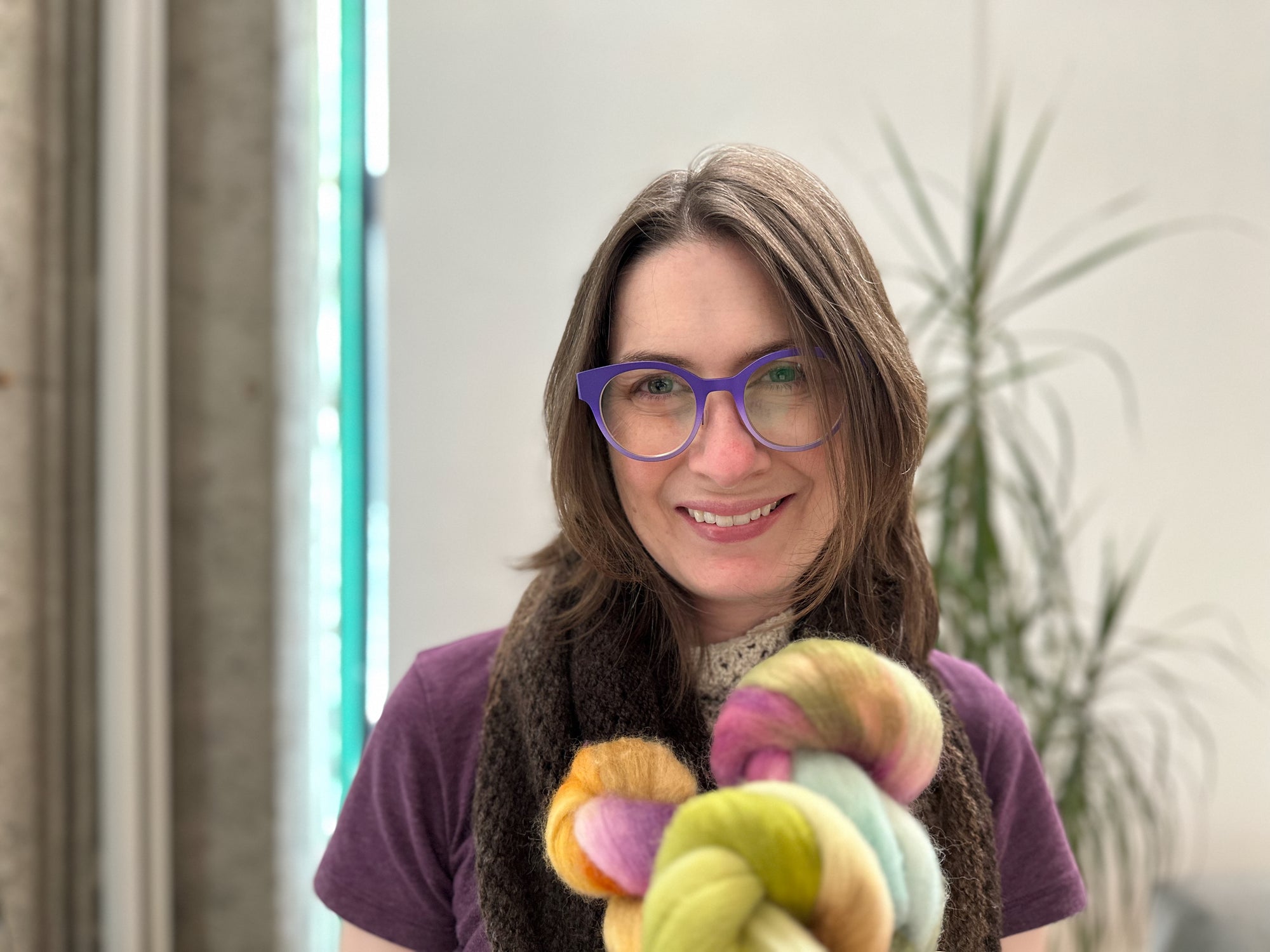 Miryha  holding colorful fiber in an indoor setting